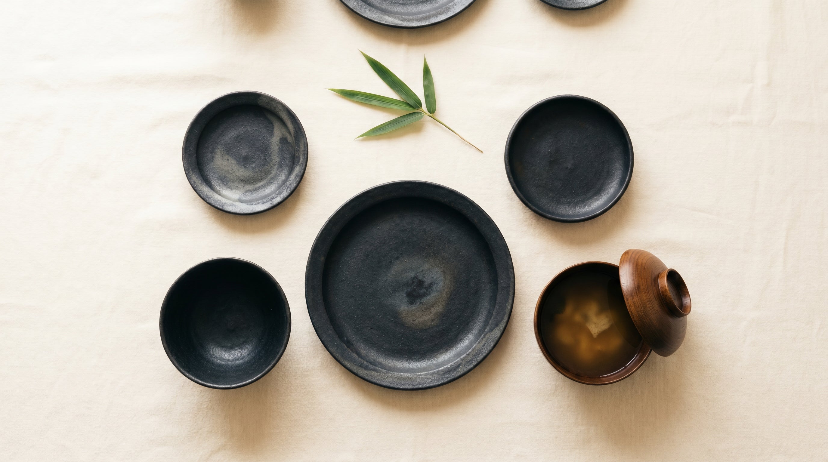 A serene Japanese dining table setting featuring dark Suzu-yaki pottery
